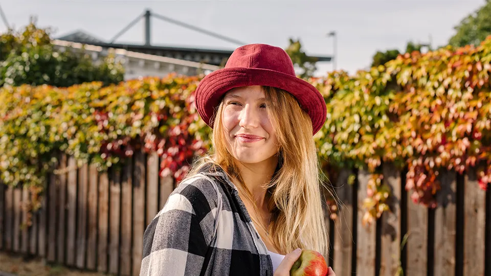 Eine duale REWE Studentin im Handel haelt einen Apfel in der Hand